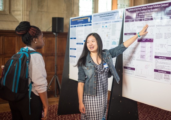 Student shows a poster while another student looks on