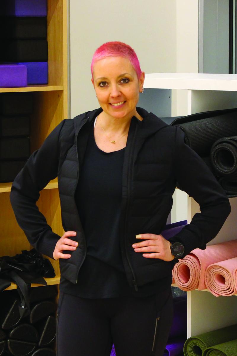 Portrait of Courtney Morris in front of a shelf full of yoga mats