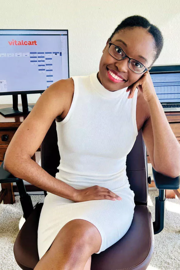 Portrait of Adaobi Kanu seated in front of a computer, the monitor displaying the Vitalcart extension