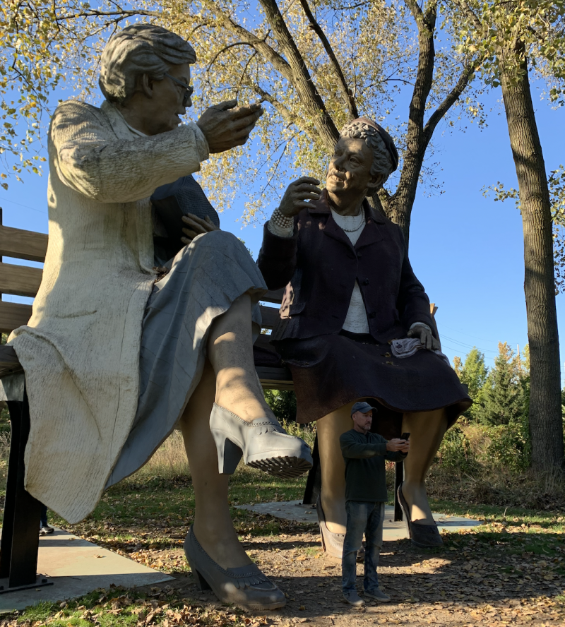 Sculpture of two figures on a bench. 