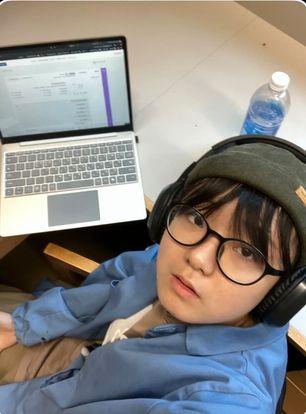 Student taking a selfie with laptop on desk. 