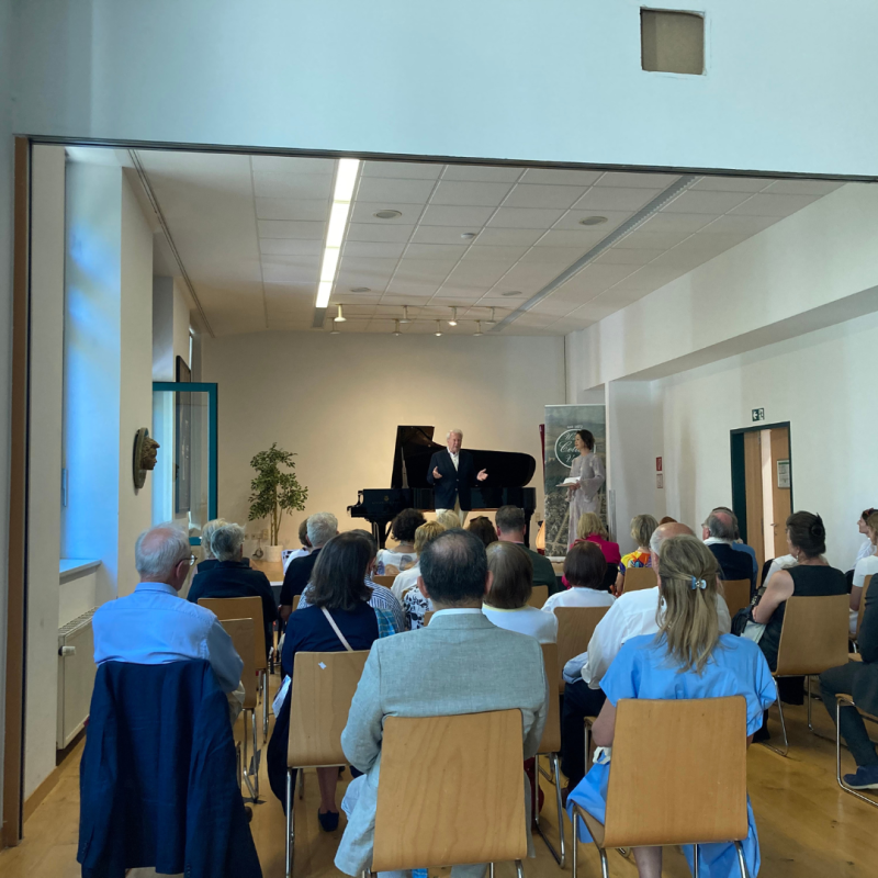 Back of an audience seated and watching a pianist perform