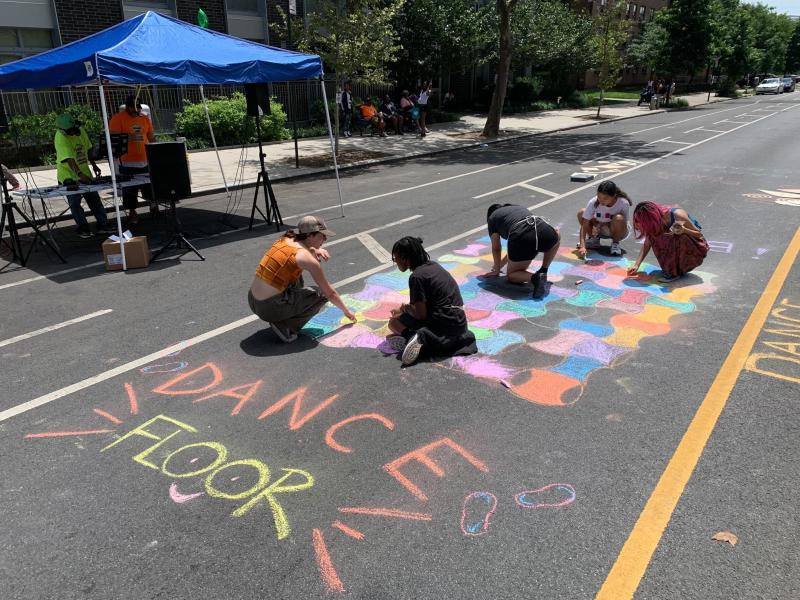 People doing chalk art on a street. 