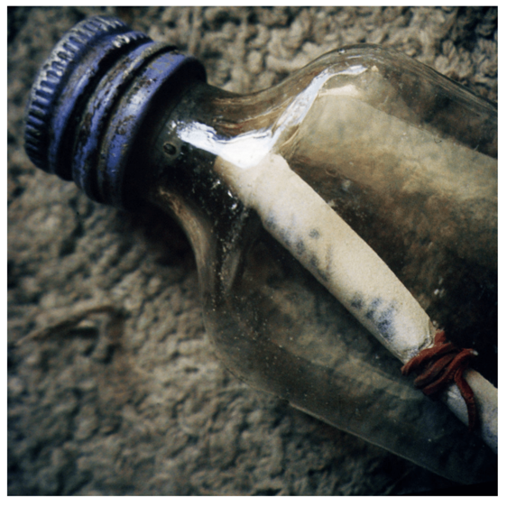 Close up photograph of capped bottle with scrolled paper inside