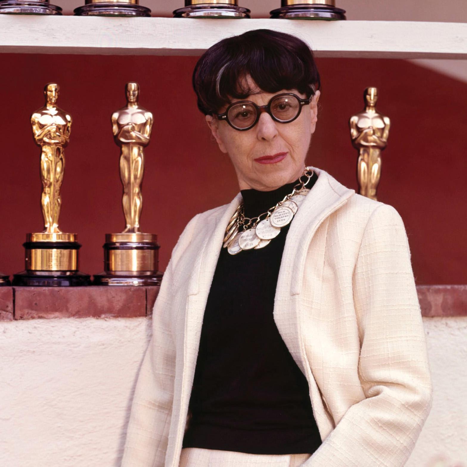 Portrait of Edith Head in front of Academy Award statuettes